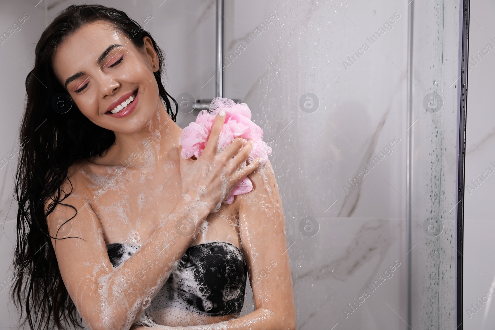 Young woman with mesh pouf taking shower at home. Space for text Photo of Young woman with mesh pouf taking shower at home. Space for text