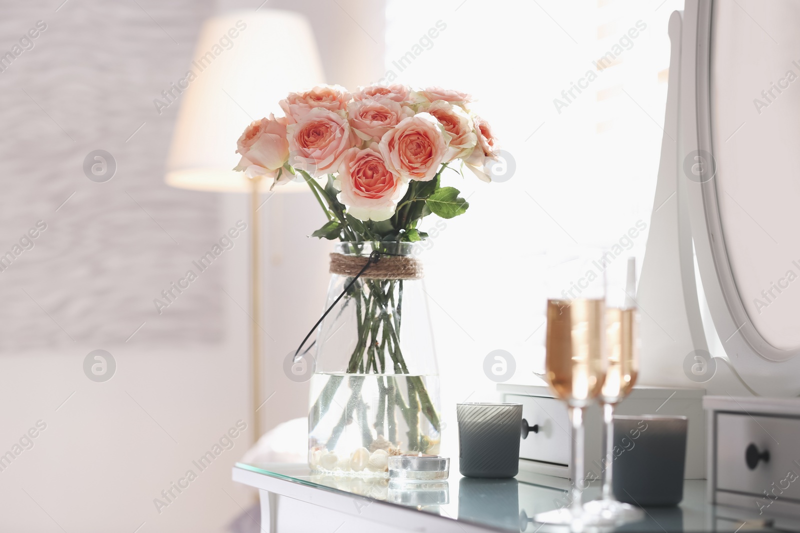 Glass vase with beautiful flowers on dressing table in modern room interior Photo of Glass vase with beautiful flowers on dressing table in modern room interior