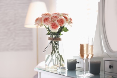 Glass vase with beautiful flowers on dressing table in modern room interior Photo of Glass vase with beautiful flowers on dressing table in modern room interior