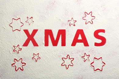 Word XMAS and snowflakes made of flour on red background, top view Photo of Word XMAS and snowflakes made of flour on red background, top view