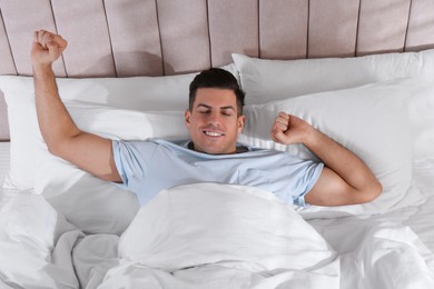 Man awakening in comfortable bed with white linens, above view Photo of Man awakening in comfortable bed with white linens, above view
