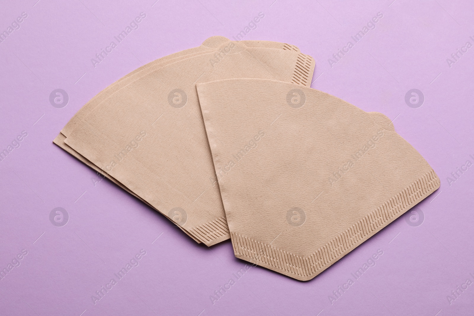 Photo of Paper coffee filters on lilac background, flat lay