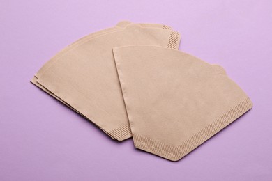 Paper coffee filters on lilac background, flat lay Photo of Paper coffee filters on lilac background, flat lay
