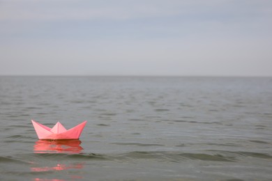 Pink paper boat on water surface, space for text Photo of Pink paper boat on water surface, space for text