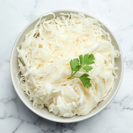 Photo of Tasty fermented cabbage with parsley on white marble table, top view