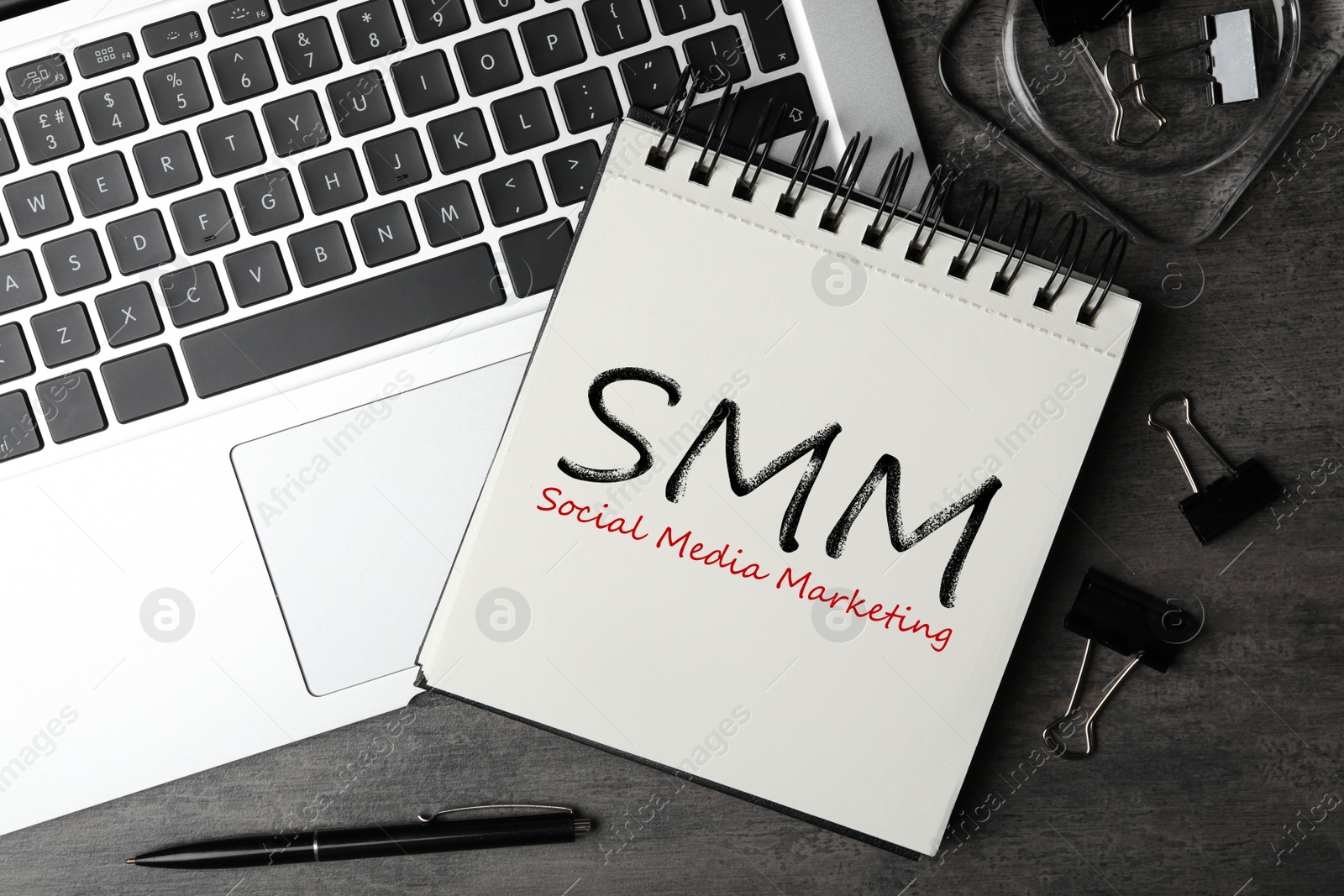 Notebook with text SMM (Social media marketing) and laptop on grey table, flat lay Image of Notebook with text SMM (Social media marketing) and laptop on grey table, flat lay