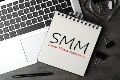 Notebook with text SMM (Social media marketing) and laptop on grey table, flat lay Image of Notebook with text SMM (Social media marketing) and laptop on grey table, flat lay