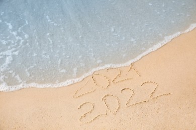 Dates written on sandy beach. 2021 washed by sea wave as New 2022 Year coming Photo of Dates written on sandy beach. 2021 washed by sea wave as New 2022 Year coming