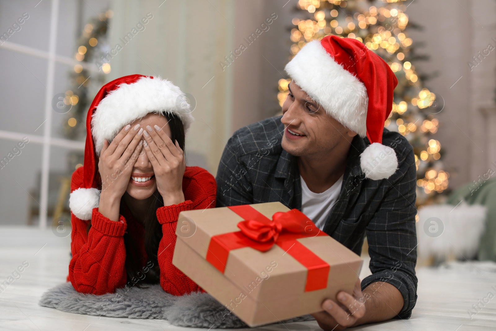 Man presenting Christmas gift to his girlfriend at home Photo of Man presenting Christmas gift to his girlfriend at home