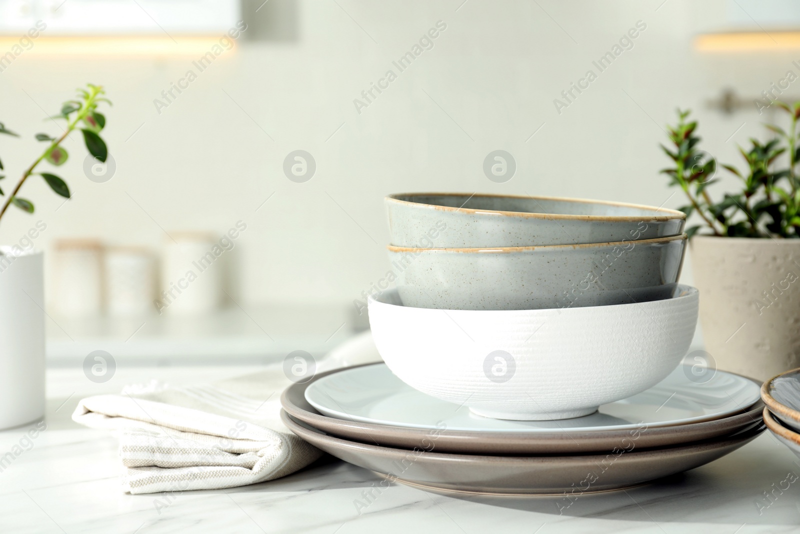 Set of beautiful ceramic tableware on white table in kitchen. Space for text Photo of Set of beautiful ceramic tableware on white table in kitchen. Space for text