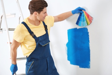 Male decorator holding color palette samples indoors Photo of Male decorator holding color palette samples indoors