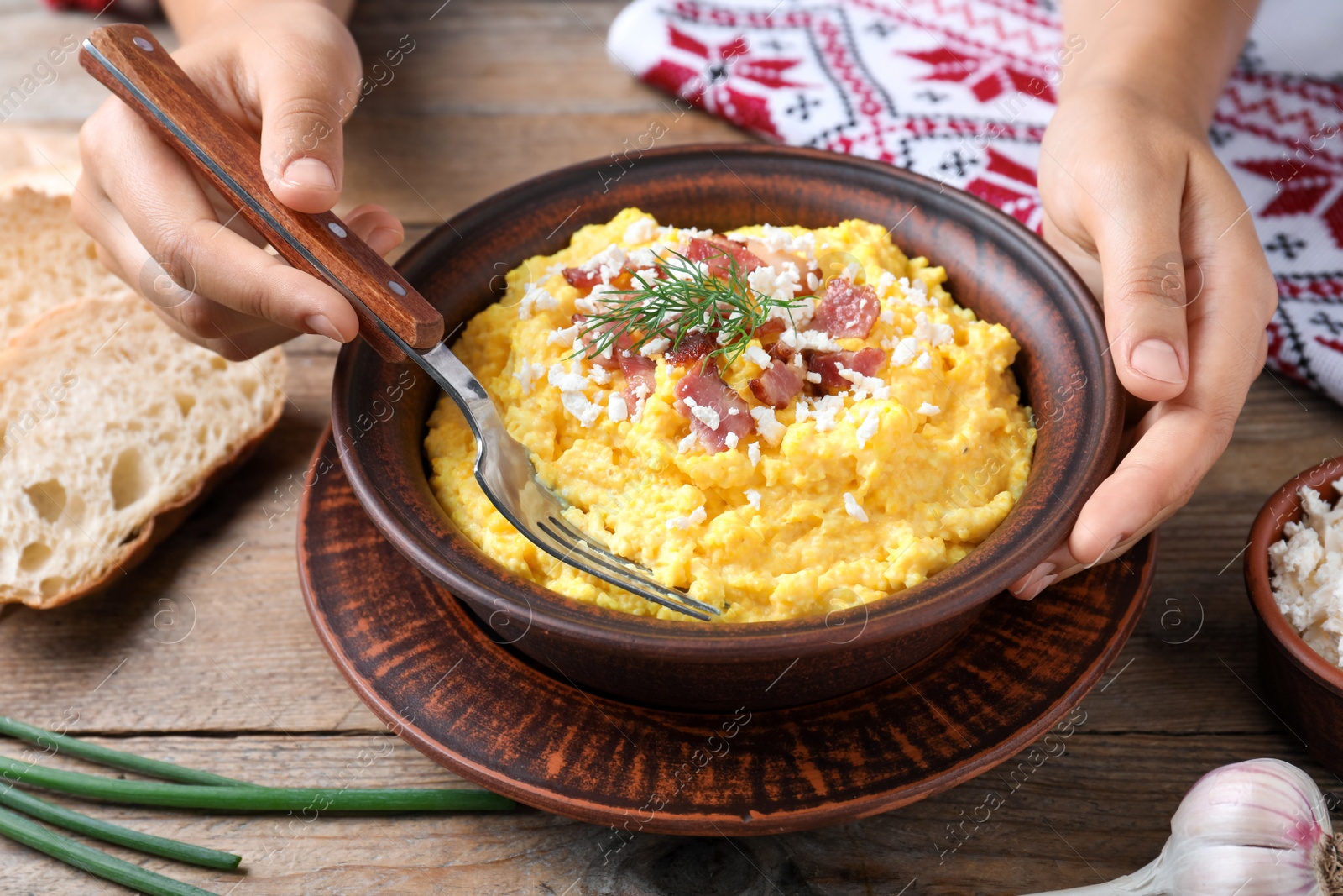 Woman eating banosh with brynza and pork cracklings at wooden table, closeup. Traditional Ukrainian dish Photo of Woman eating banosh with brynza and pork cracklings at wooden table, closeup. Traditional Ukrainian dish