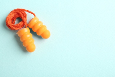 Pair of orange ear plugs with cord on turquoise background, top view. Space for text Photo of Pair of orange ear plugs with cord on turquoise background, top view. Space for text