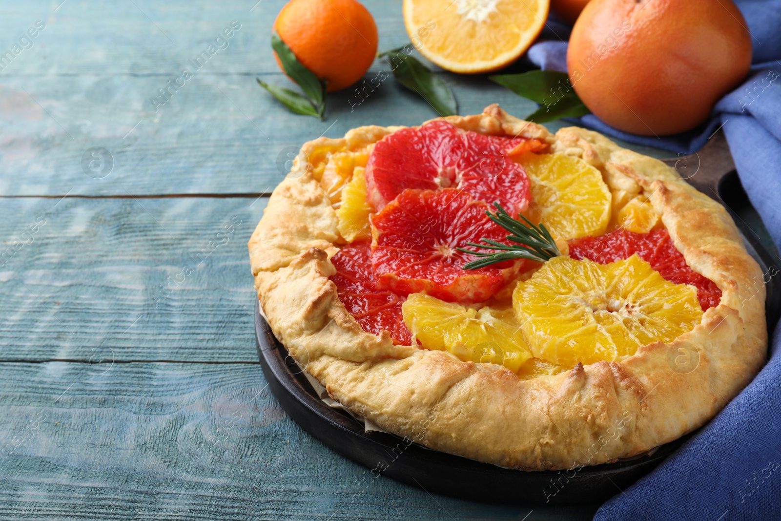 Delicious galette with citrus fruits and rosemary on blue wooden table Photo of Delicious galette with citrus fruits and rosemary on blue wooden table
