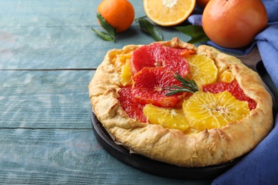 Delicious galette with citrus fruits and rosemary on blue wooden table Photo of Delicious galette with citrus fruits and rosemary on blue wooden table