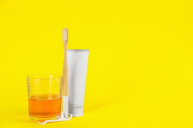 Mouthwash, toothbrush, paste and dental floss pick on yellow background, space for text Photo of Mouthwash, toothbrush, paste and dental floss pick on yellow background, space for text