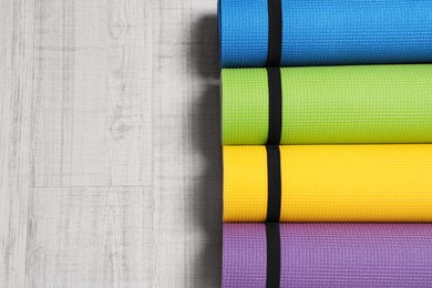 Bright rolled camping mats on white wooden background, flat lay. Space for text Photo of Bright rolled camping mats on white wooden background, flat lay. Space for text