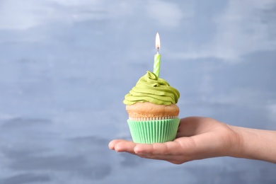 Woman holding birthday cupcake on blurred background Photo of Woman holding birthday cupcake on blurred background