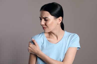 Woman suffering from shoulder pain on beige background Photo of Woman suffering from shoulder pain on beige background