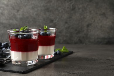 Delicious panna cotta with fruit coulis and fresh blueberries served on grey table. Space for text Photo of Delicious panna cotta with fruit coulis and fresh blueberries served on grey table. Space for text