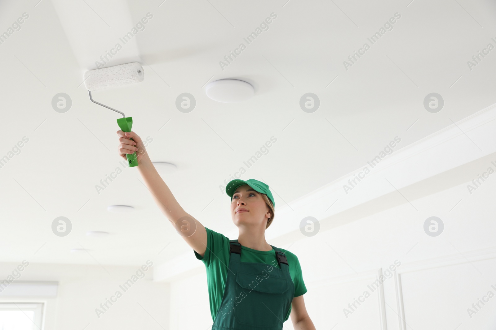 Worker painting ceiling with white dye indoors Photo of Worker painting ceiling with white dye indoors