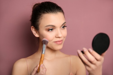 Young woman applying makeup on color background. Professional cosmetic products Photo of Young woman applying makeup on color background. Professional cosmetic products