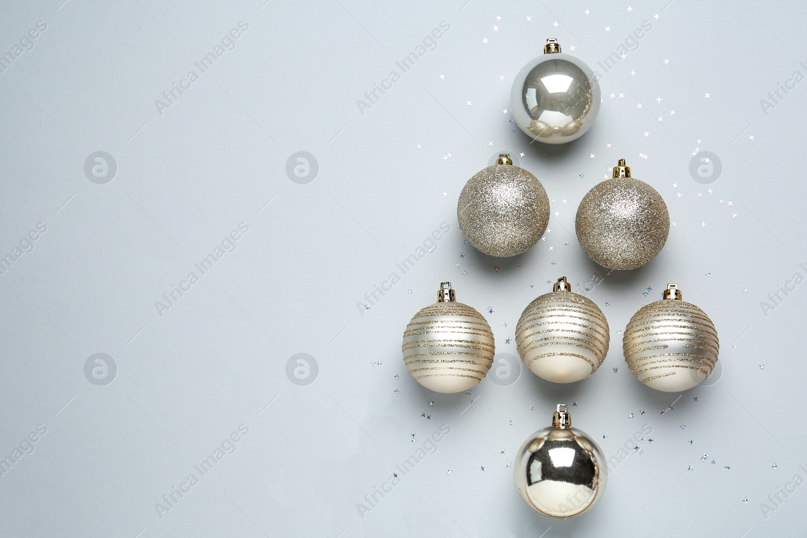 Christmas tree shape made of decorative balls on light background, flat lay. Space for text Photo of Christmas tree shape made of decorative balls on light background, flat lay. Space for text