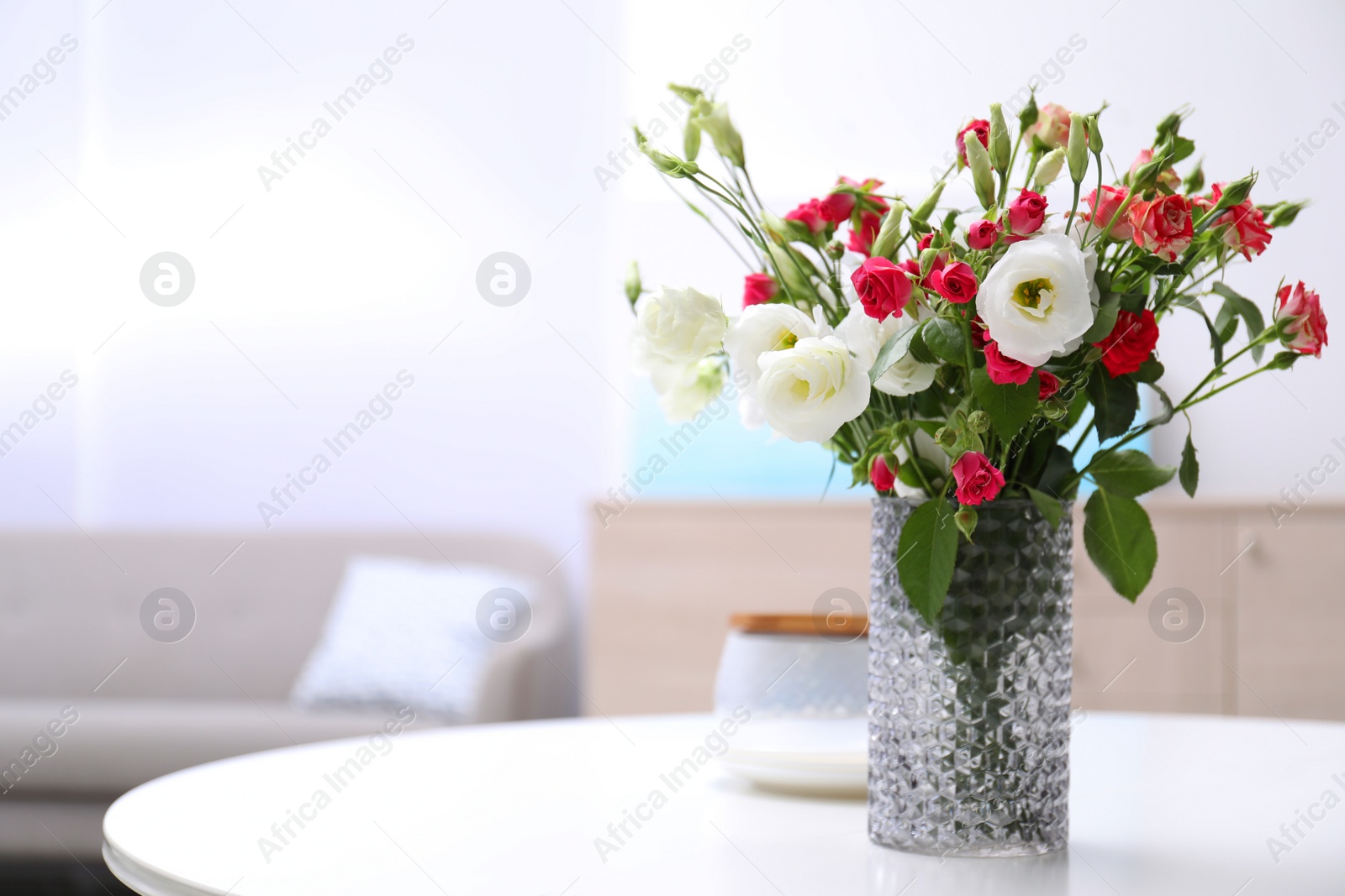 Vase with beautiful flowers on white table in room, space for text Photo of Vase with beautiful flowers on white table in room, space for text