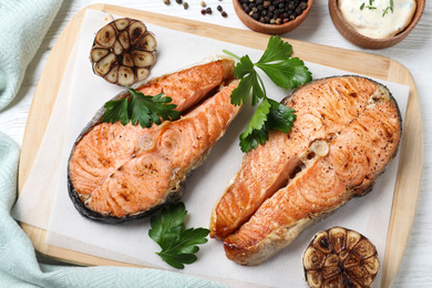 Tasty cooked red fish on white wooden table, flat lay Photo of Tasty cooked red fish on white wooden table, flat lay