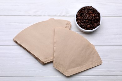 Paper coffee filters and beans on white wooden table, flat lay Photo of Paper coffee filters and beans on white wooden table, flat lay