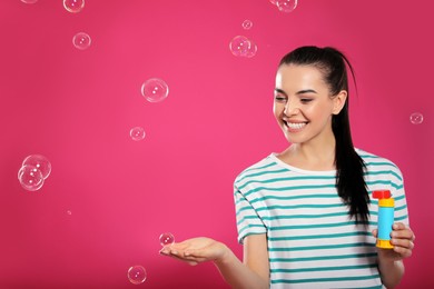 Young woman having fun with soap bubbles on pink background, space for text Photo of Young woman having fun with soap bubbles on pink background, space for text