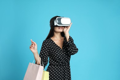 Woman with shopping bags using virtual reality headset on light blue background Photo of Woman with shopping bags using virtual reality headset on light blue background