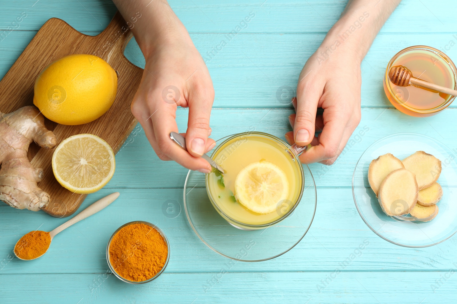 Woman with cup of immunity boosting drink at turquoise wooden table, top view Photo of Woman with cup of immunity boosting drink at turquoise wooden table, top view