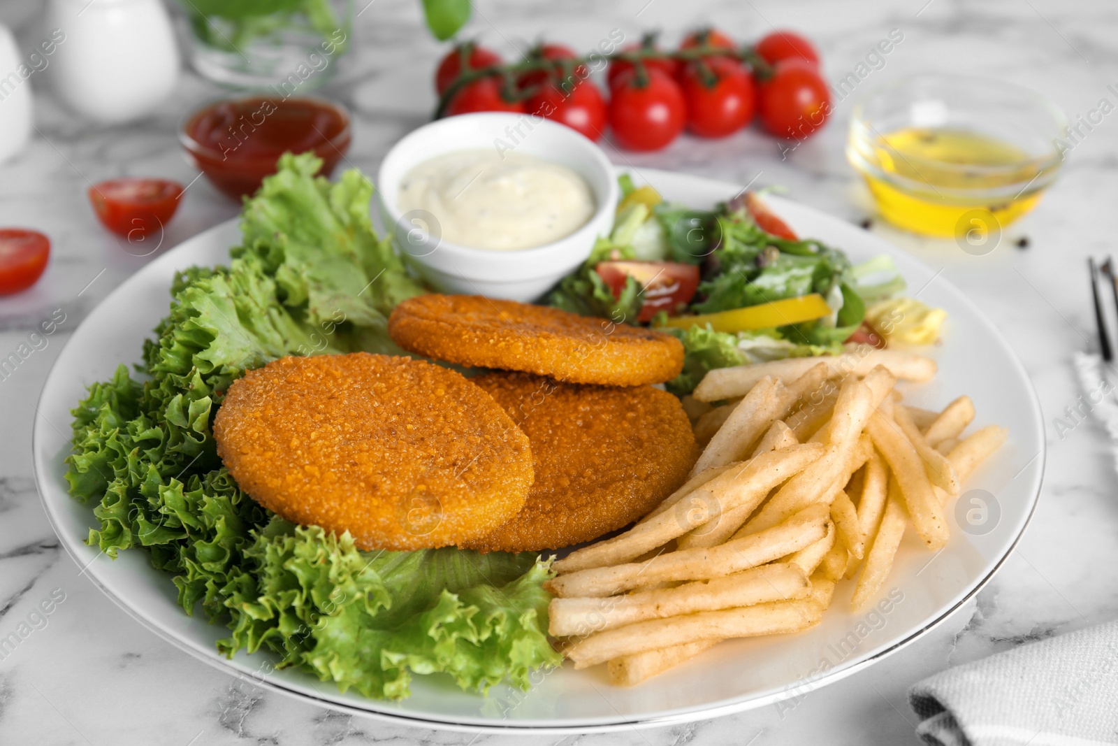 Delicious fried breaded cutlets with garnish served on white marble table Photo of Delicious fried breaded cutlets with garnish served on white marble table