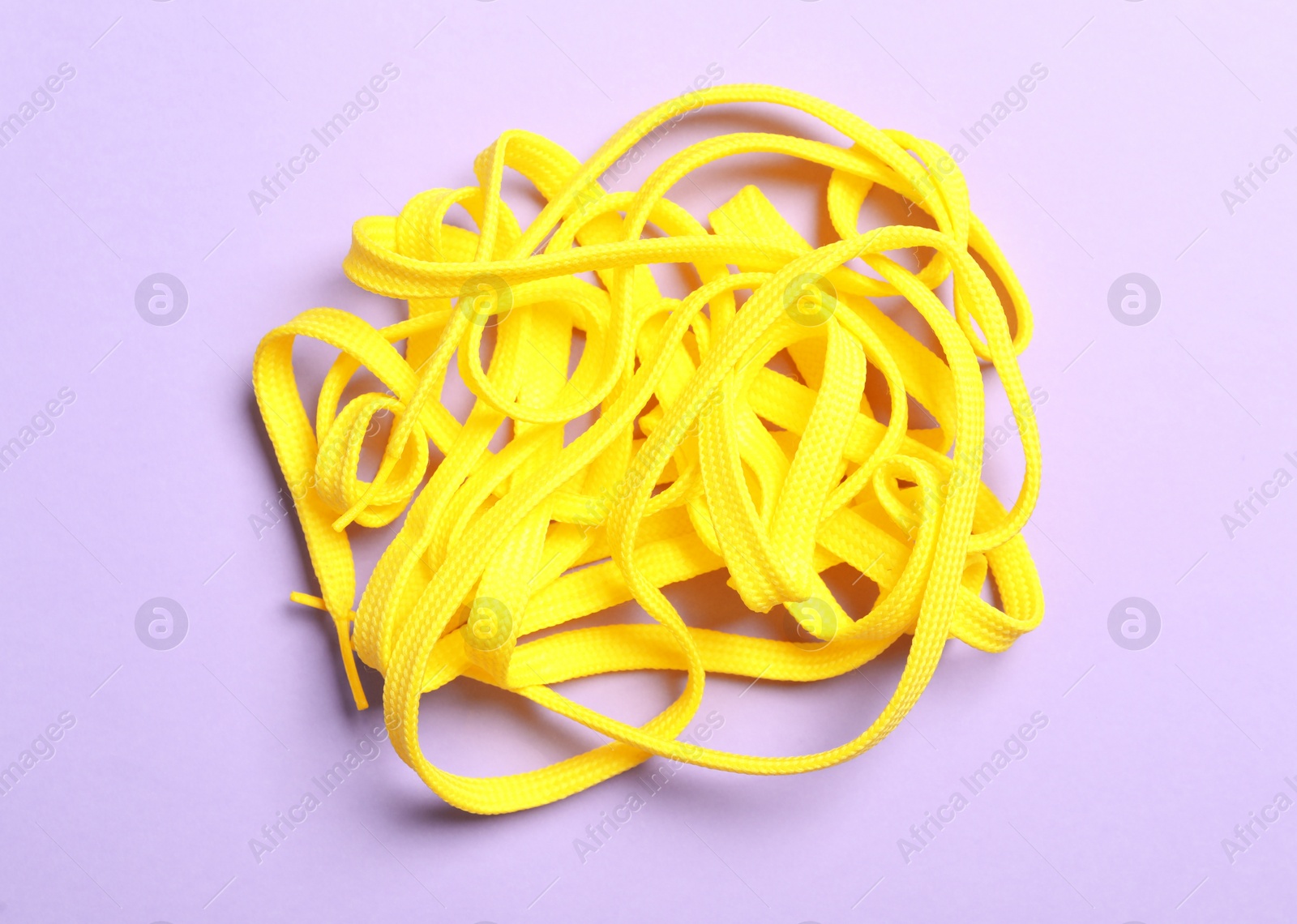 Yellow shoelaces on lilac background, flat lay Photo of Yellow shoelaces on lilac background, flat lay