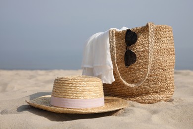 Beach bag, towel, sunglasses and hat on sandy seashore, space for text Photo of Beach bag, towel, sunglasses and hat on sandy seashore, space for text