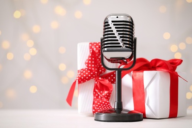 Retro microphone and gift boxes on table against blurred lights, space for text. Christmas music Photo of Retro microphone and gift boxes on table against blurred lights, space for text. Christmas music