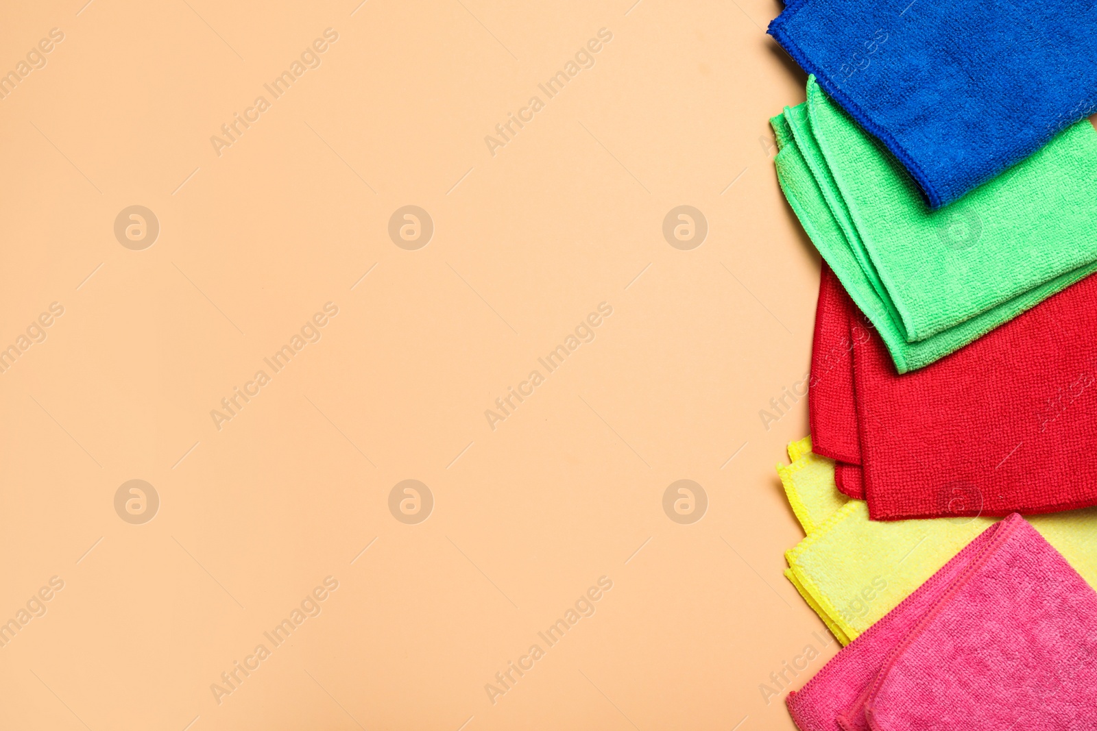 Many colorful microfiber cloths on beige background, flat lay. Space for text Photo of Many colorful microfiber cloths on beige background, flat lay. Space for text