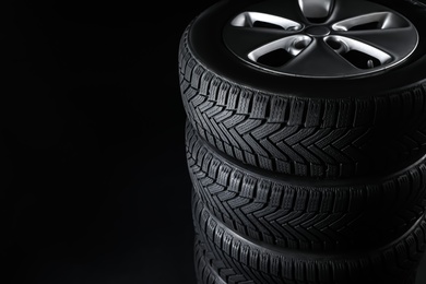 Set of wheels with winter tires on black background, closeup. Space for text Photo of Set of wheels with winter tires on black background, closeup. Space for text