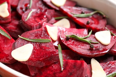 Raw beetroot slices, garlic and rosemary in baking dish, closeup Photo of Raw beetroot slices, garlic and rosemary in baking dish, closeup
