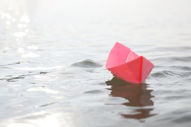 Pink paper boat on water surface, space for text Photo of Pink paper boat on water surface, space for text
