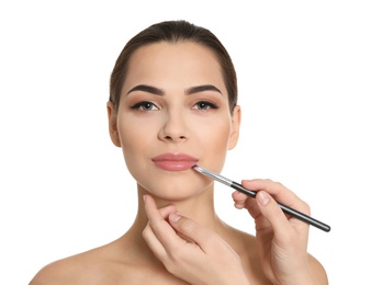 Visage artist applying makeup on woman's face against white background. Professional cosmetic products Photo of Visage artist applying makeup on woman's face against white background. Professional cosmetic products