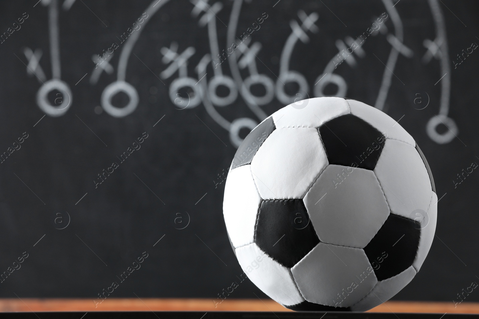 Football ball against blurred game scheme. Space for text Photo of Football ball against blurred game scheme. Space for text