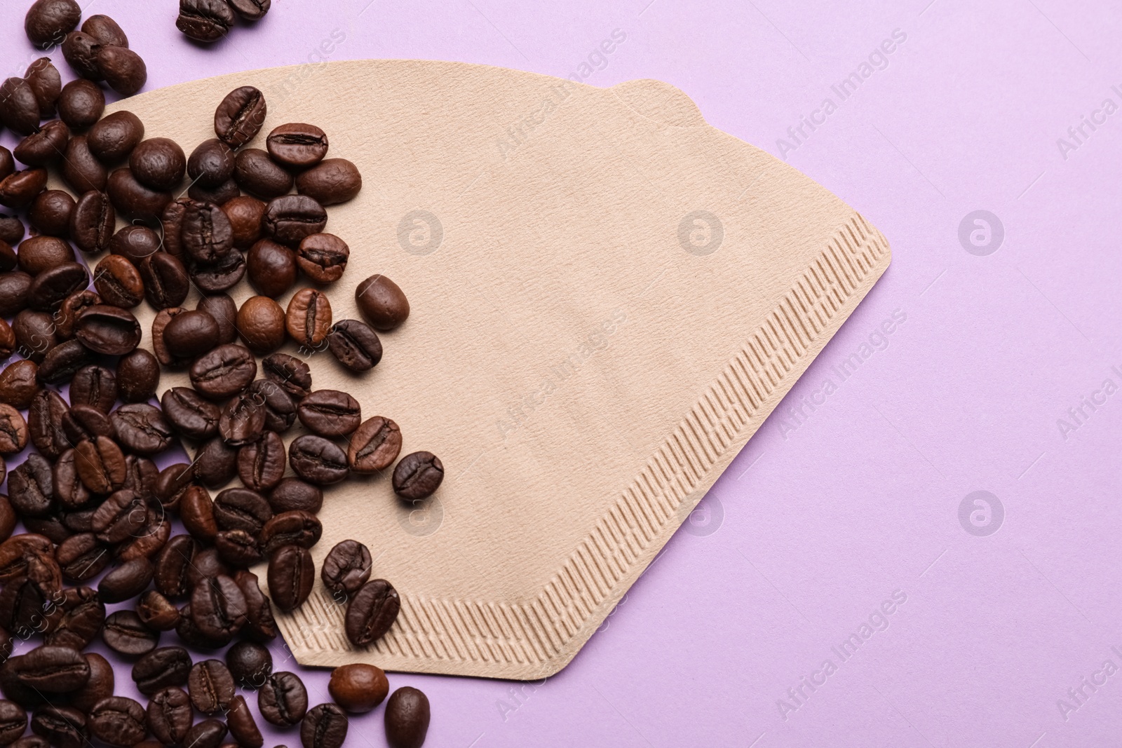 Paper coffee filter and beans on lilac background, flat lay. Space for text Photo of Paper coffee filter and beans on lilac background, flat lay. Space for text