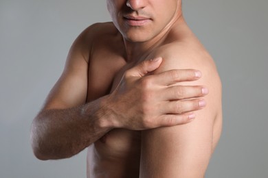Man suffering from shoulder pain on beige background, closeup Photo of Man suffering from shoulder pain on beige background, closeup
