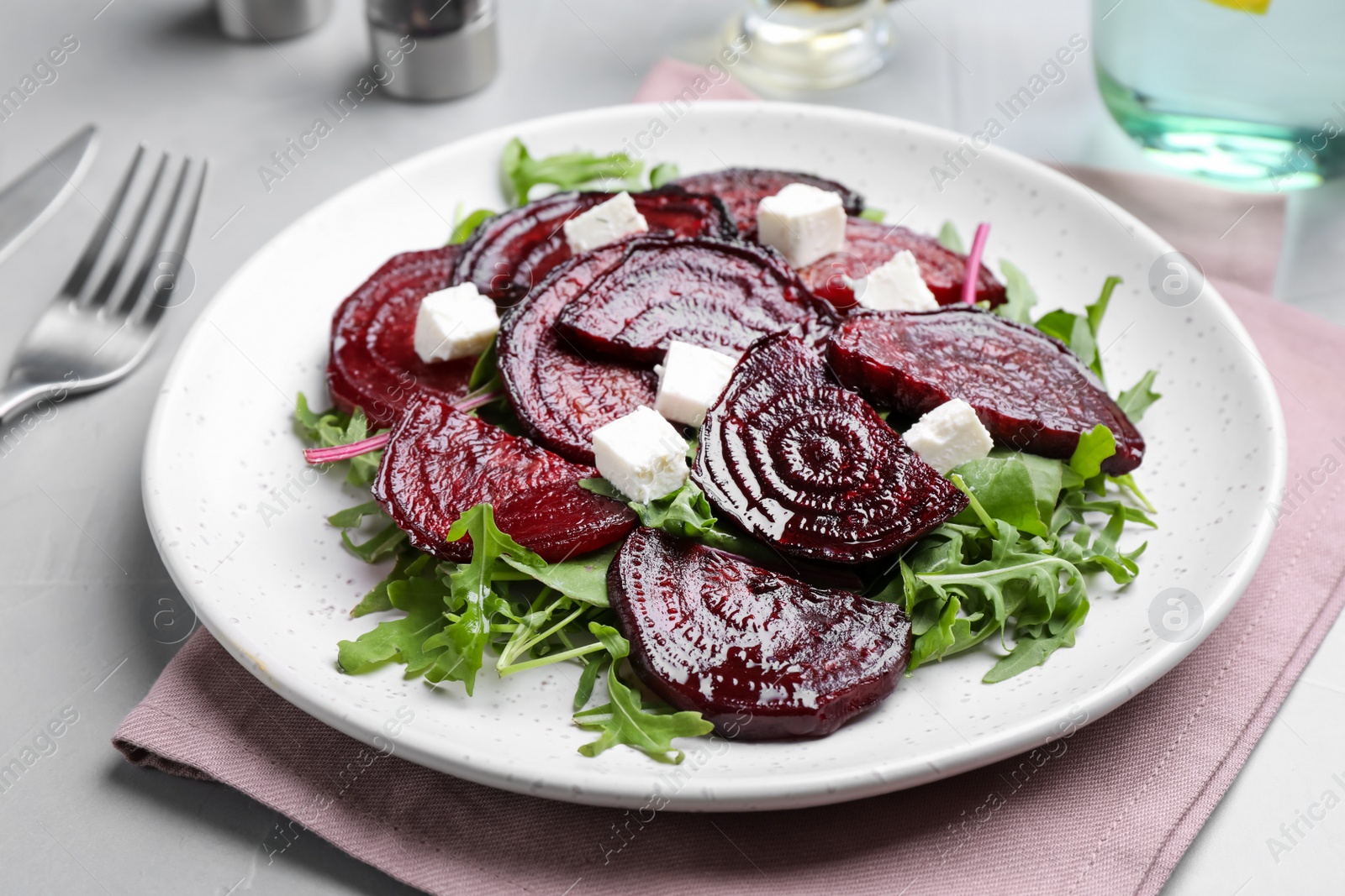 Roasted beetroot slices with feta cheese and arugula on light grey table, closeup Photo of Roasted beetroot slices with feta cheese and arugula on light grey table, closeup