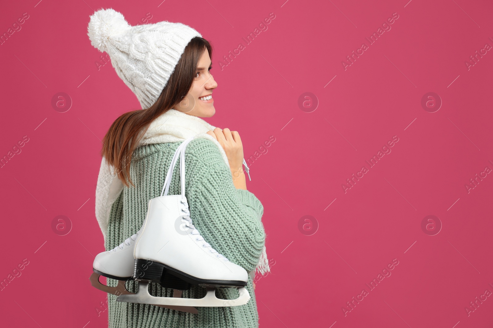 Happy woman with ice skates on pink background. Space for text Photo of Happy woman with ice skates on pink background. Space for text