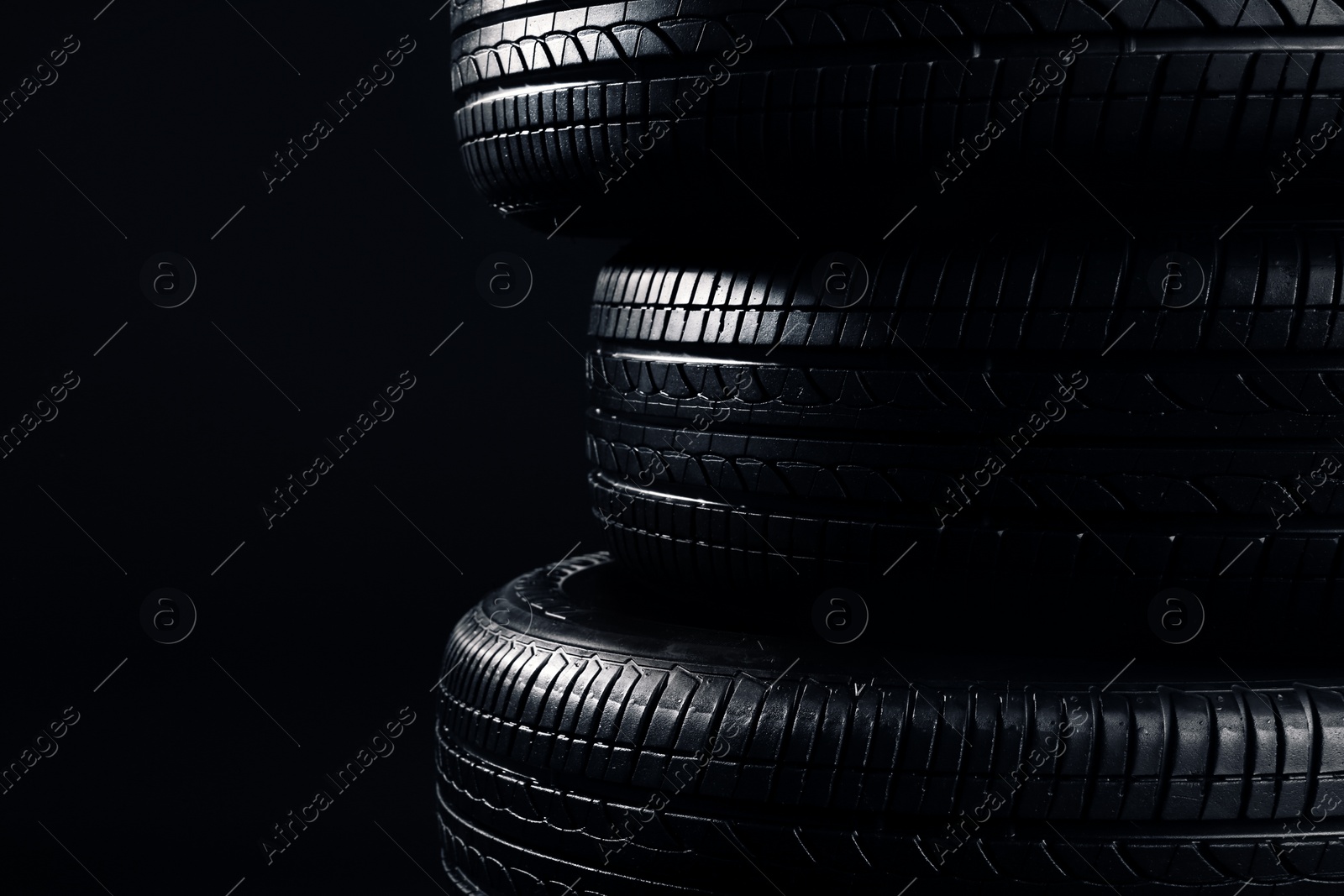 Stack of car tires on black background, closeup Photo of Stack of car tires on black background, closeup