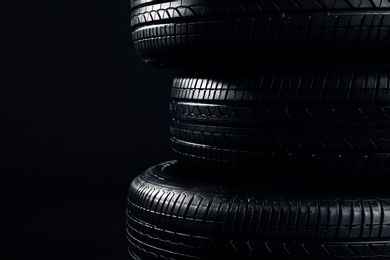 Stack of car tires on black background, closeup Photo of Stack of car tires on black background, closeup