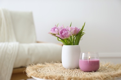 Vase with beautiful flowers and burning candle on table indoors, space for text. Interior elements Photo of Vase with beautiful flowers and burning candle on table indoors, space for text. Interior elements